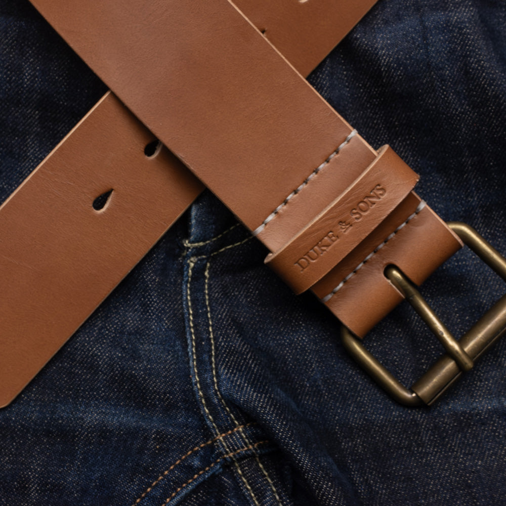 Duke and Sons 2-inch cognac leather jeans belt with old bronze buckle crossed on jeans hero image