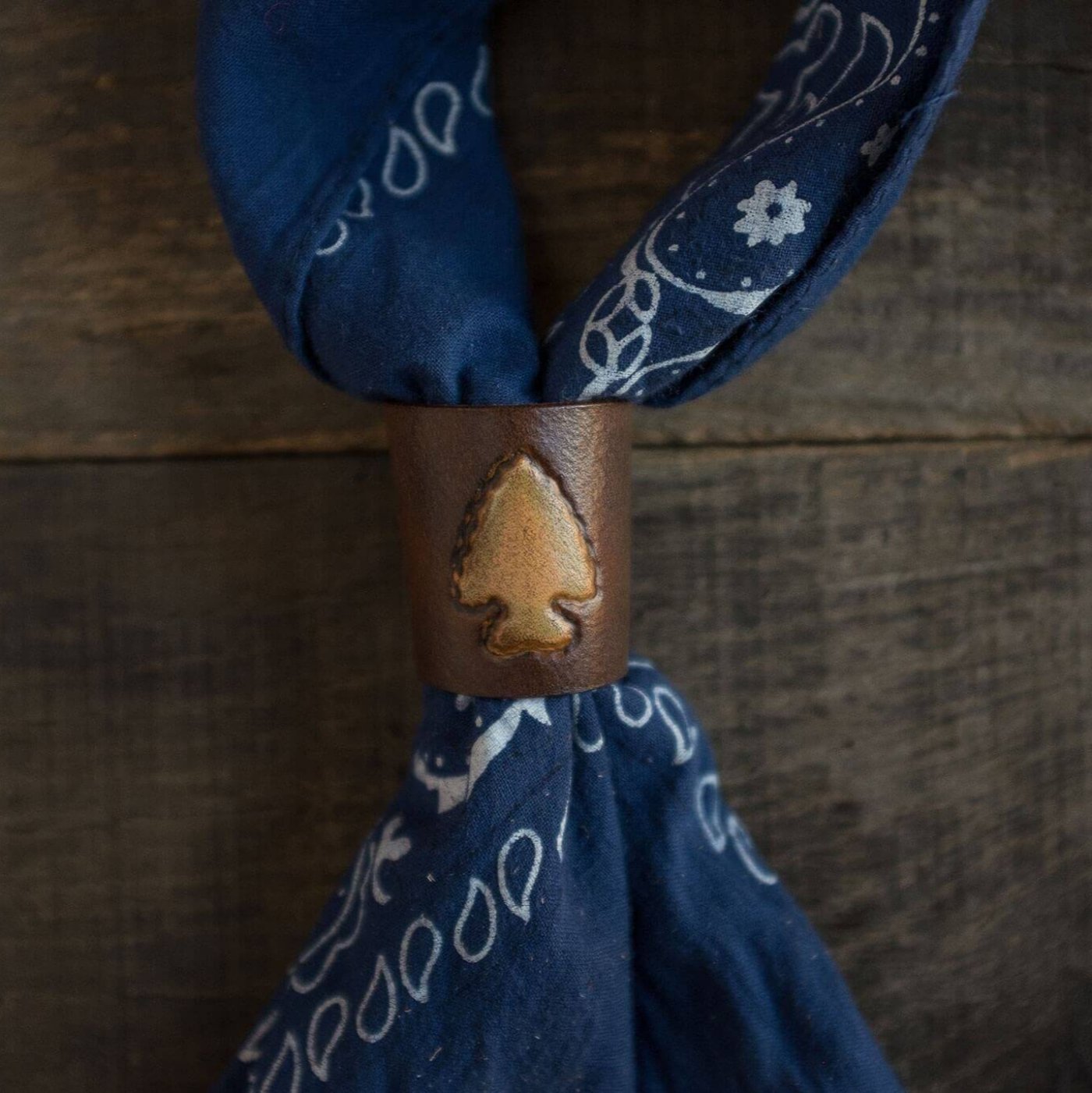 Woggle, bandana / neckerchief slide made from leather with an arrow point image stamp around a blue bandana