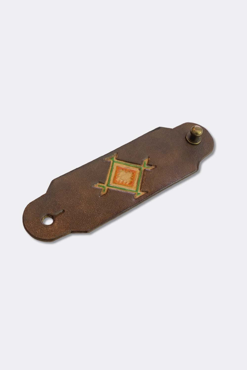 Woggle, bandana / neckerchief slide in brown leather with a square native pattern stamp, slanted view