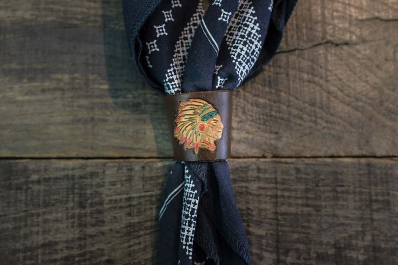 Woggle, bandana / neckerchief slide made from brown leather with an Indian Chief image stamp, around a blue bandana