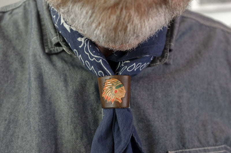 Woggle, bandana / neckerchief slide made from  brown leather with an Indian Chief image stamp, wearing around a blue bandana