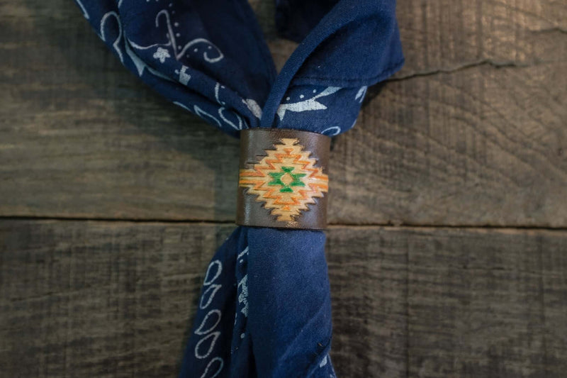 Woggle, bandana / neckerchief slide in brown leather with a rectangle native pattern stamp, around a blue bandana