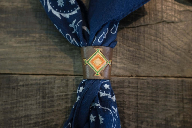 Woggle, bandana / neckerchief slide in brown leather with a square native pattern stamp, around a blue bandana