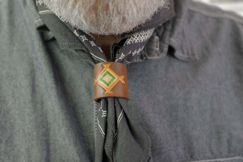 Woggle, bandana / neckerchief slide in cognac leather with a square native pattern stamp, wearing around a blue bandana