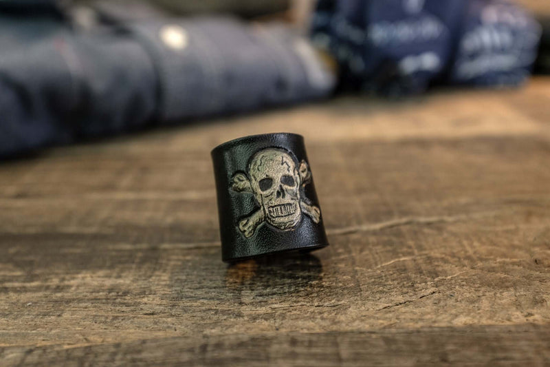 Woggle, bandana / neckerchief slide in black leather with a skull image stamp, close-up view
