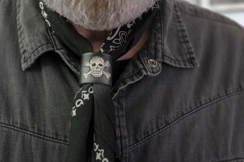 Woggle, bandana / neckerchief slide in black leather with a skull image stamp, wearing around a black bandana
