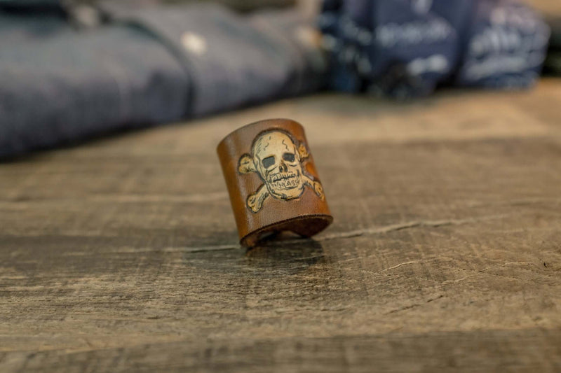 Woggle, bandana / neckerchief slide in cognac leather with a skull image stamp, close-up view