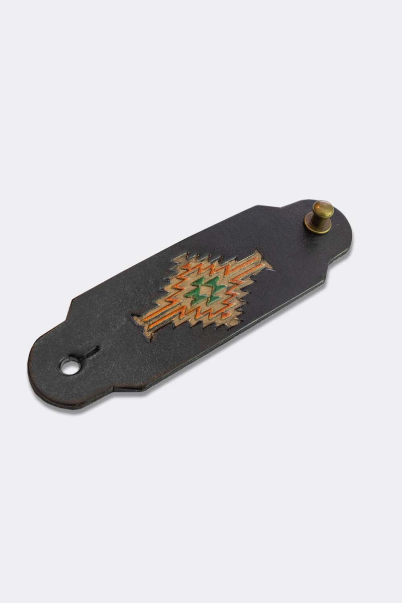 Woggle, bandana / neckerchief slide in black leather with a rectangle native pattern stamp, slanted view