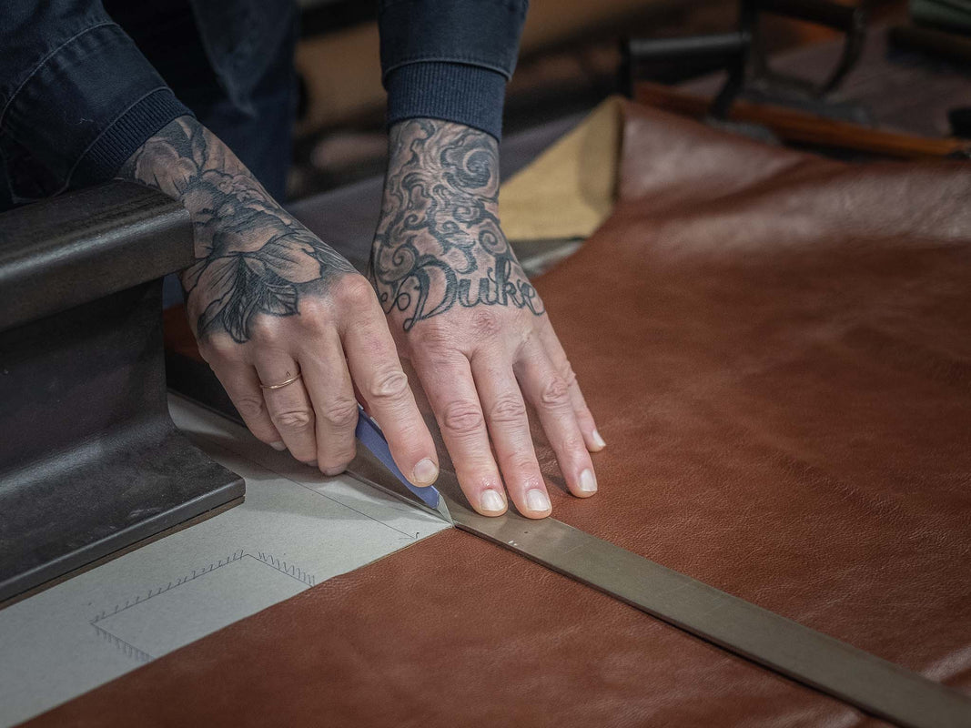 The Duke is cutting leather at Duke & Sons Leather workshop