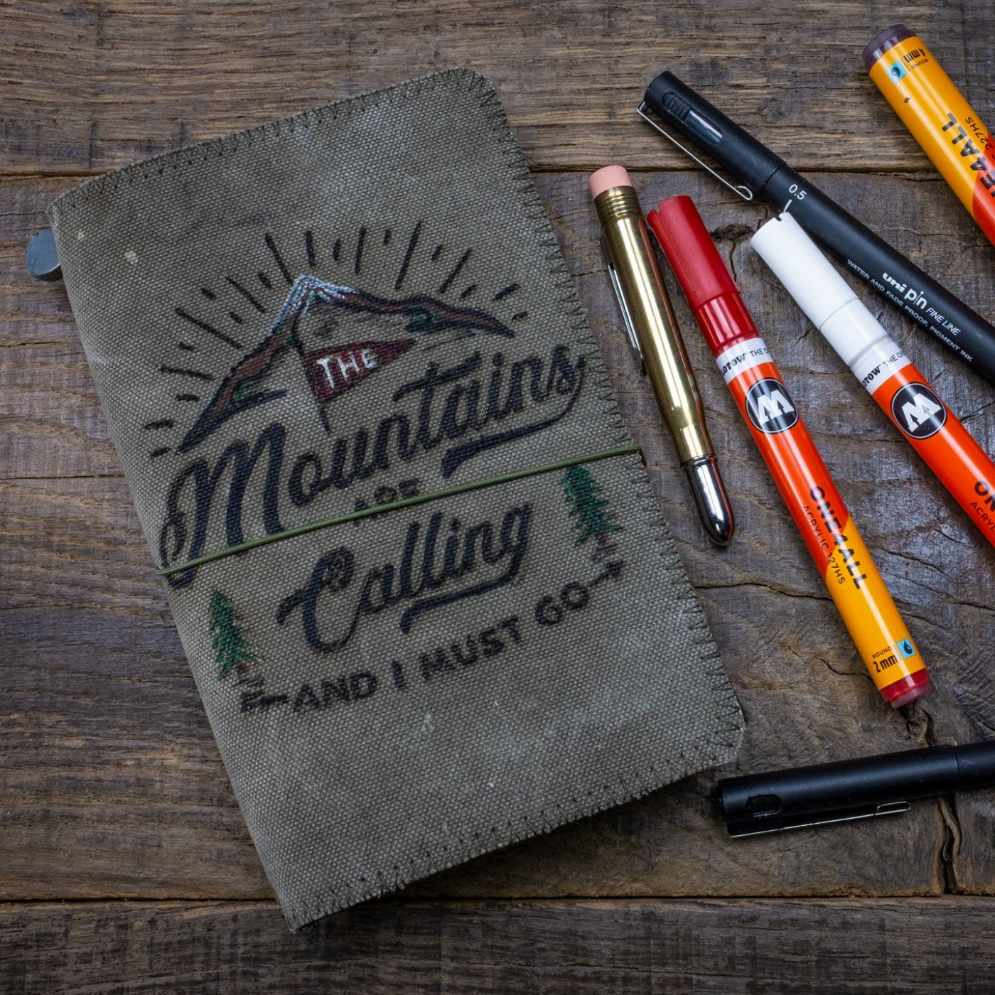 Duke and Sons traveler's notebook 'Mountains' logo canvas cover front with pens scene