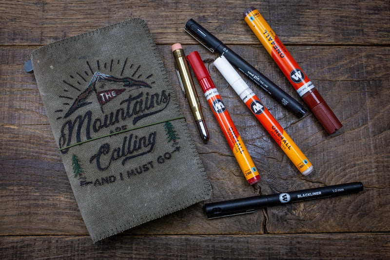 Duke and Sons traveler's notebook 'Mountains' logo canvas cover front with pens scene