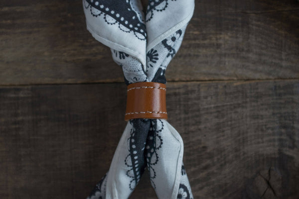 Woggle, bandana / neckerchief slide - in cognac color around a blasck and white bandana. Duke & Sons Leather