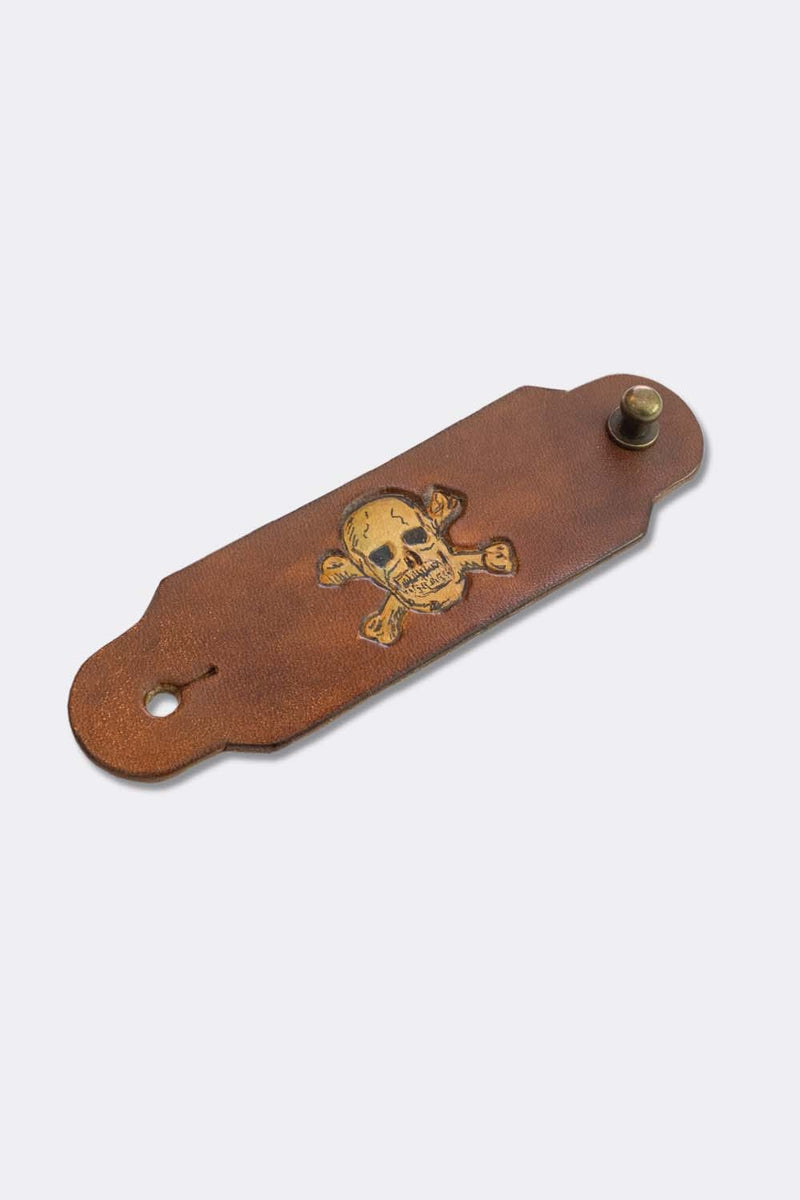 Woggle, bandana / neckerchief slide in cognac leather with a skull image stamp, slanted view