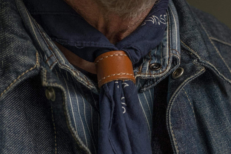 Woggle, bandana / neckerchief slide - in conac color wearing around a blue bandana in a denim jacket. Duke & Sons Leather