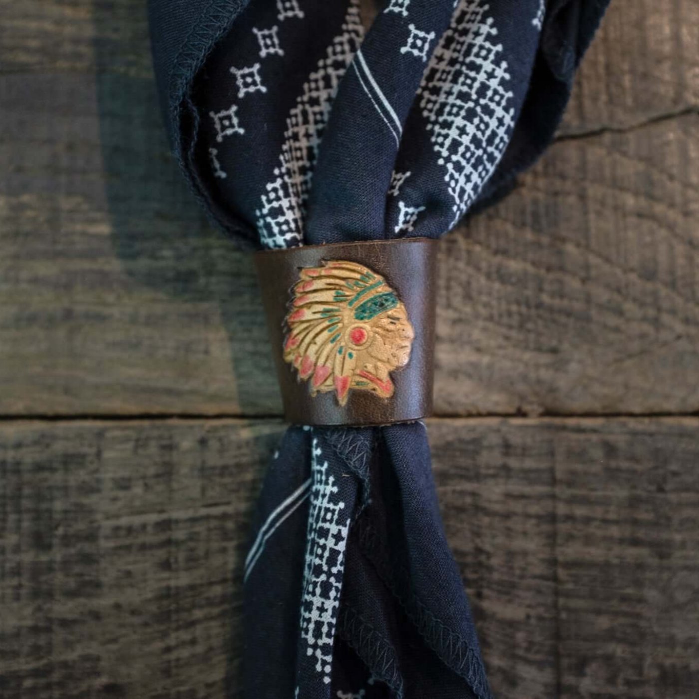 Woggle, bandana / neckerchief slide made from brown leather with an Indian Chief image stamp, around a blue bandana