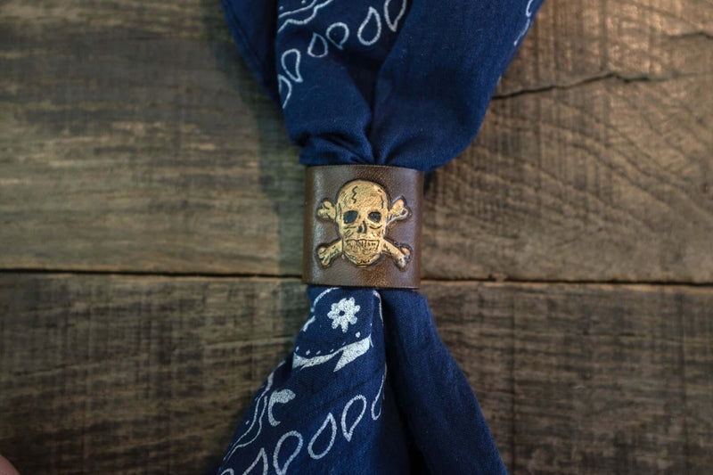 Woggle, bandana / neckerchief slide in brown leather with a skull image stamp, around a blue bandana
